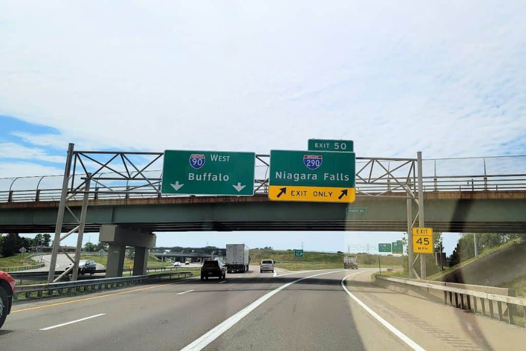 Driving on the highway under two green signs that read "Buffalo" and "Niagara Falls Exit Only"