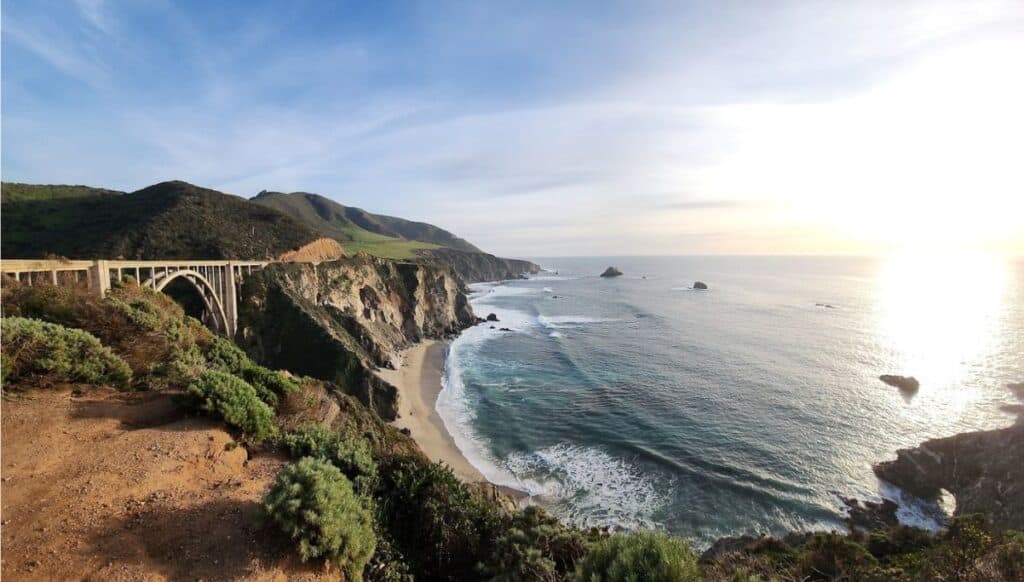 Coastal road with bridge and green mountains