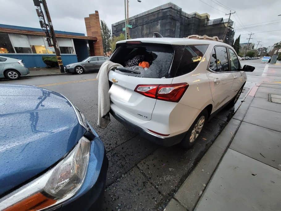 White car with back window broken and blanket hanging out