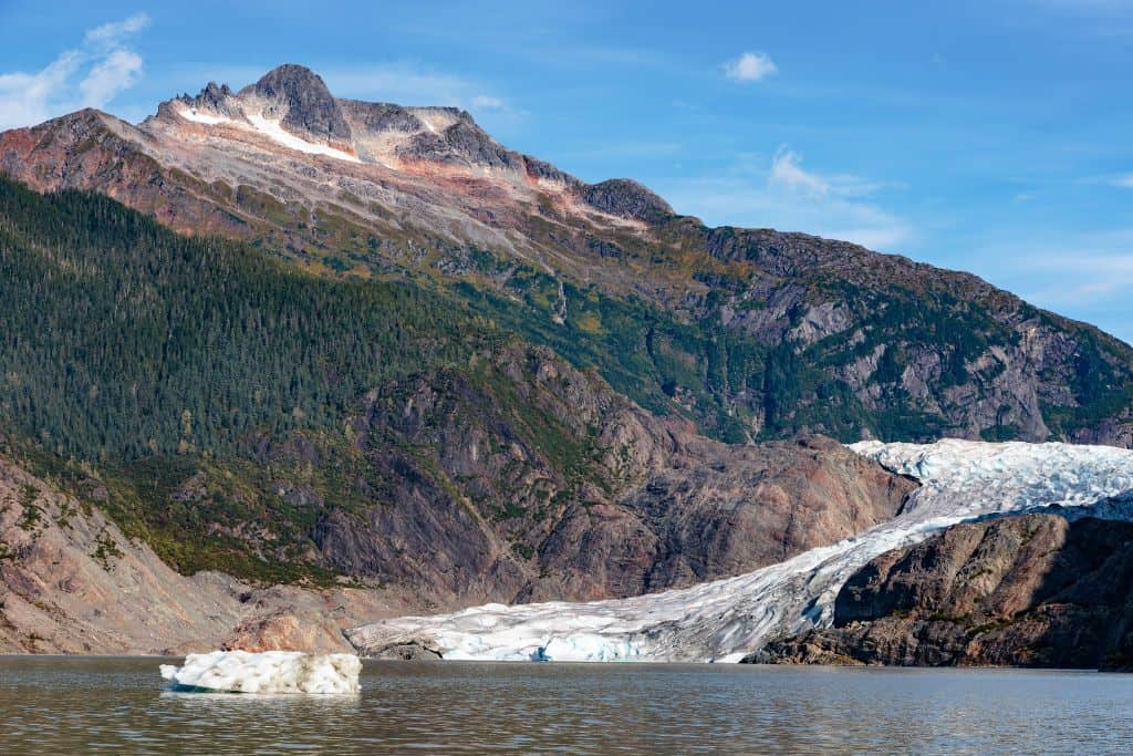 Large glacier spilling out into the ocean next to a tall, rocky mountain