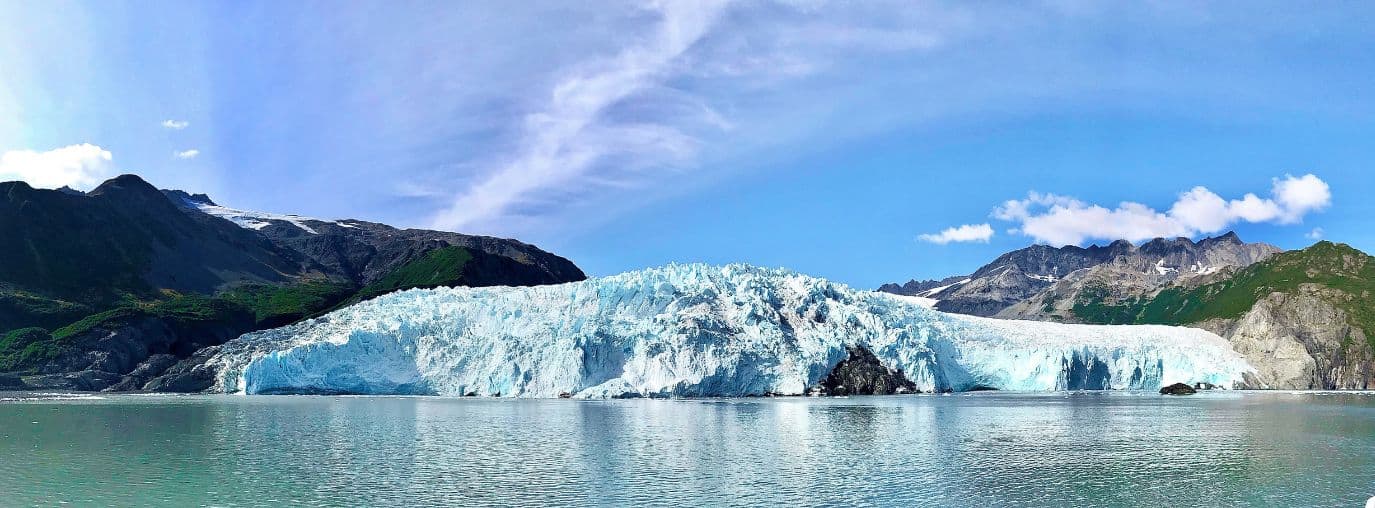 Panorama of a glacier on the ocean surrounded by rocky mountains