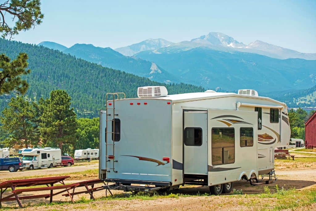 Large white RV parked in an RV park with mountains in the distance