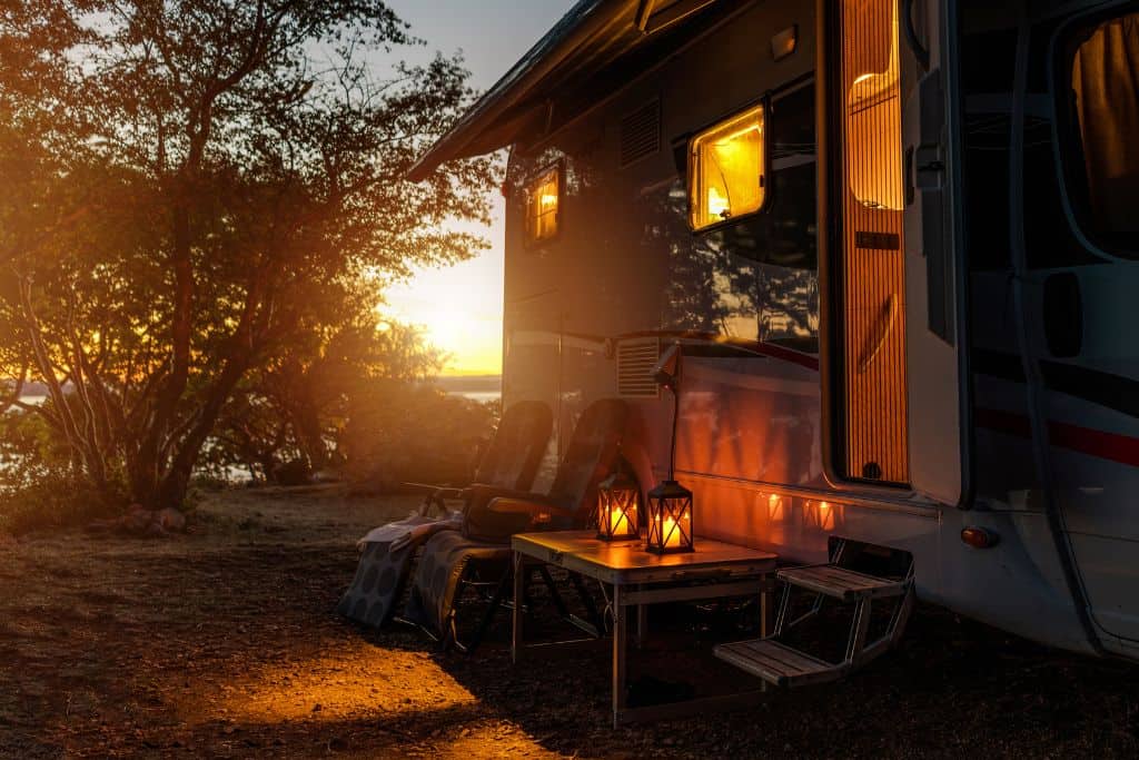 RV door open with warm lighting at sunset in a dirt RV parking spot