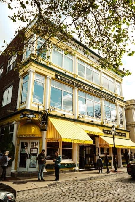 Yellow awnings on a tall, brick building on a cobblestone street