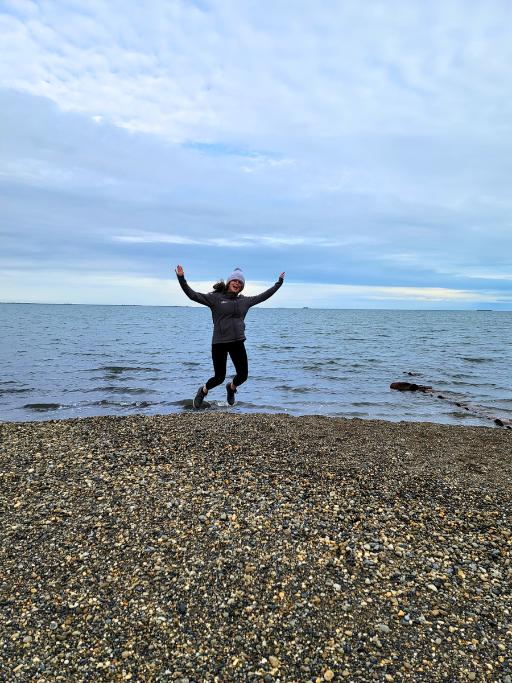 Girl jumping on a rocky beach on a cloudy day