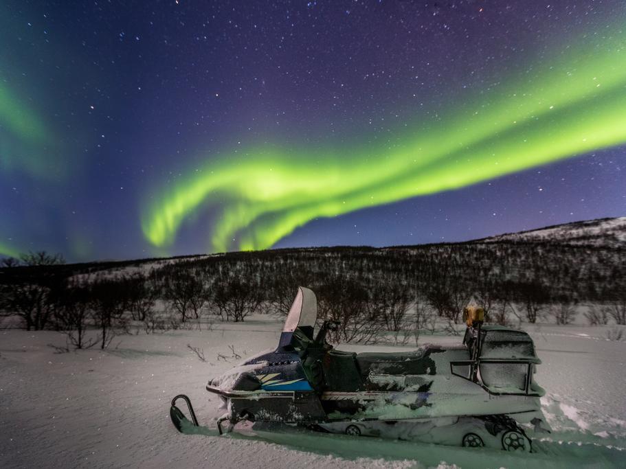 Snowmobile in a snowy field under the northern lights