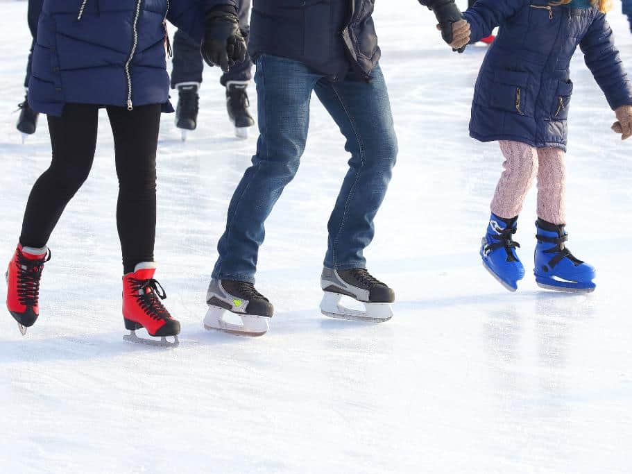 Two adults and one child holding hands while ice skating