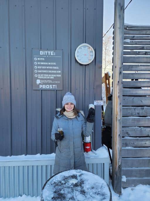 A girl standing outside pointing to a thermometer