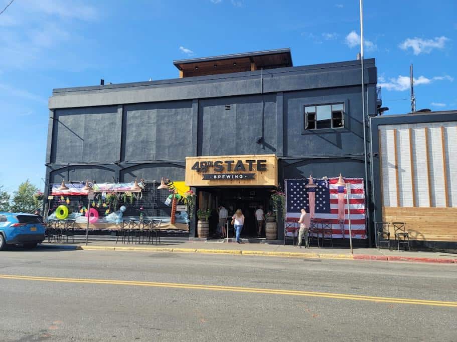 Black building with a wooden "49th State Brewing" sign