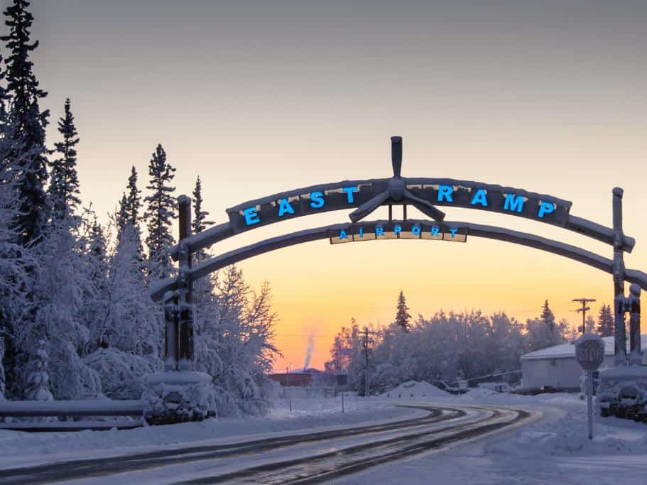 Snowy road and trees with an "East Ramp Airport" sign