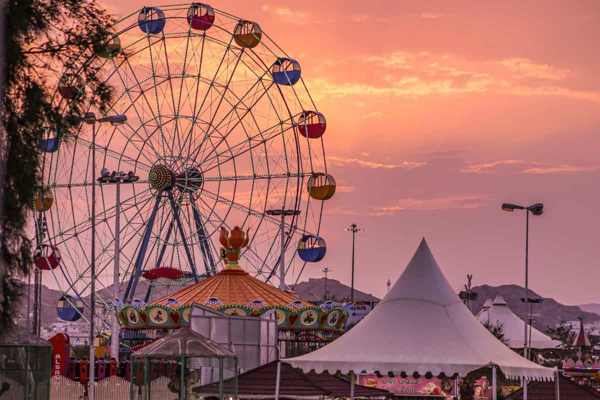 Sunset over a carnival with a ferris wheels and tall tents
