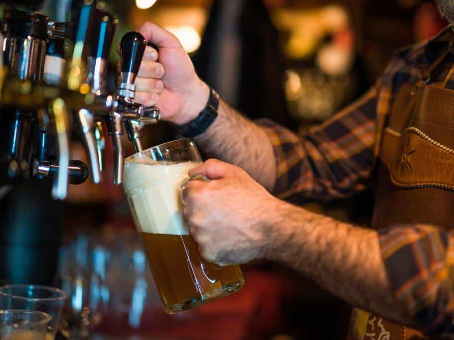 Person in a flannel pouting a large pint from a tap