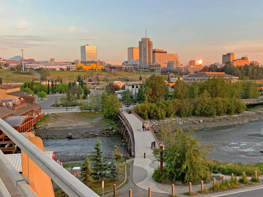 Large city with a pedestrian bridge crossing a river at sunset