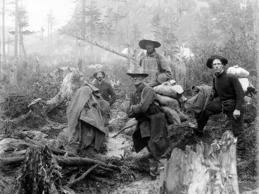 Black and white photo of prospectors looking for gold in the woods of Alaska during the Gold Rush