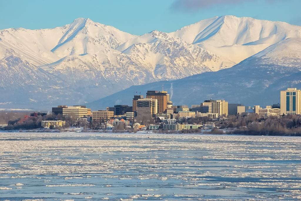 A city on an icy waterfront backed by snowy mountains