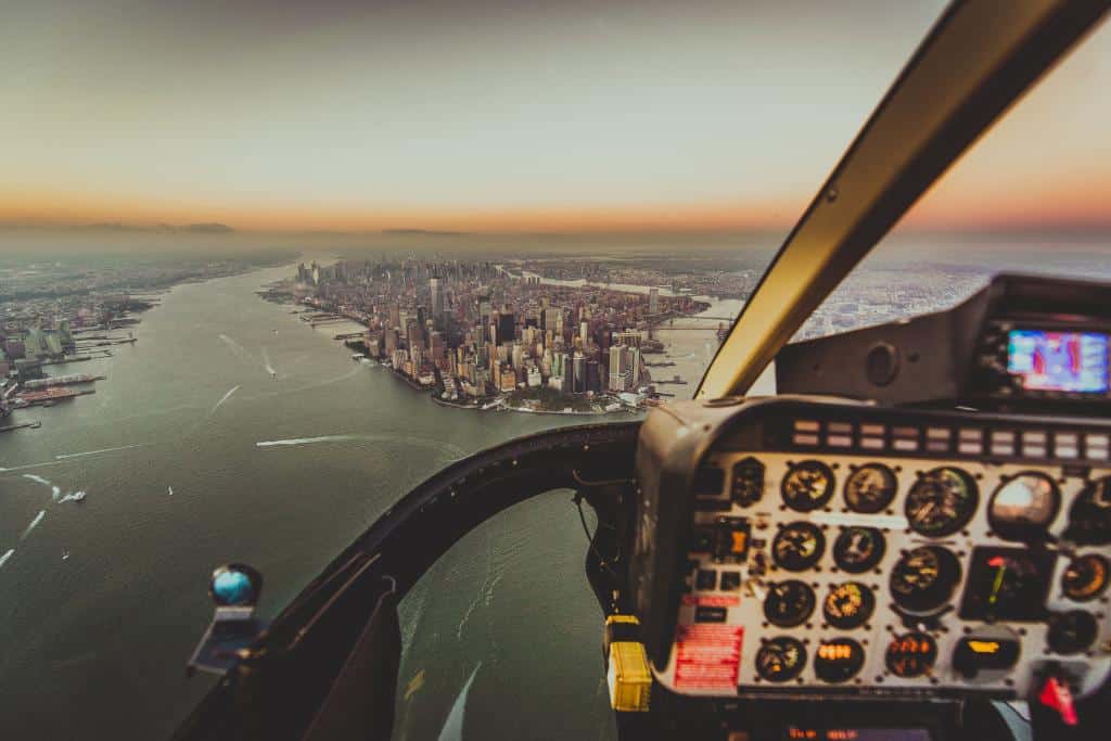 Cockpit view of a helicopter approaching a massive city surrounded by a wide river