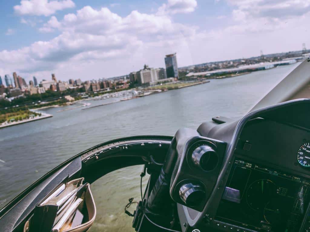 Helicopter cockpit view flying sideways over a river towards a large city