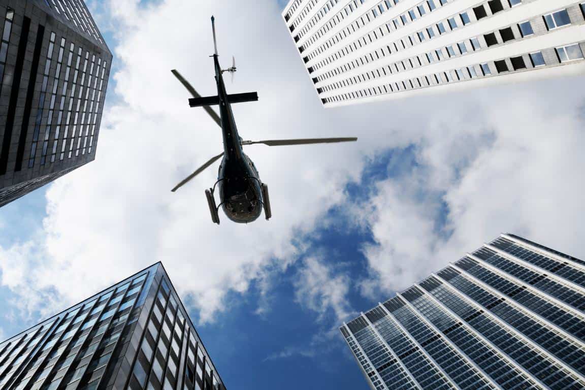 Ground view of a helicopter flying in between skyscrapers