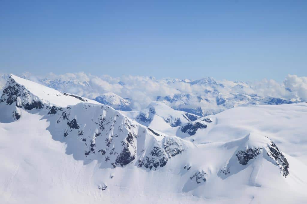 Aerial view over a large landscape of snow-covered mountains and clouds