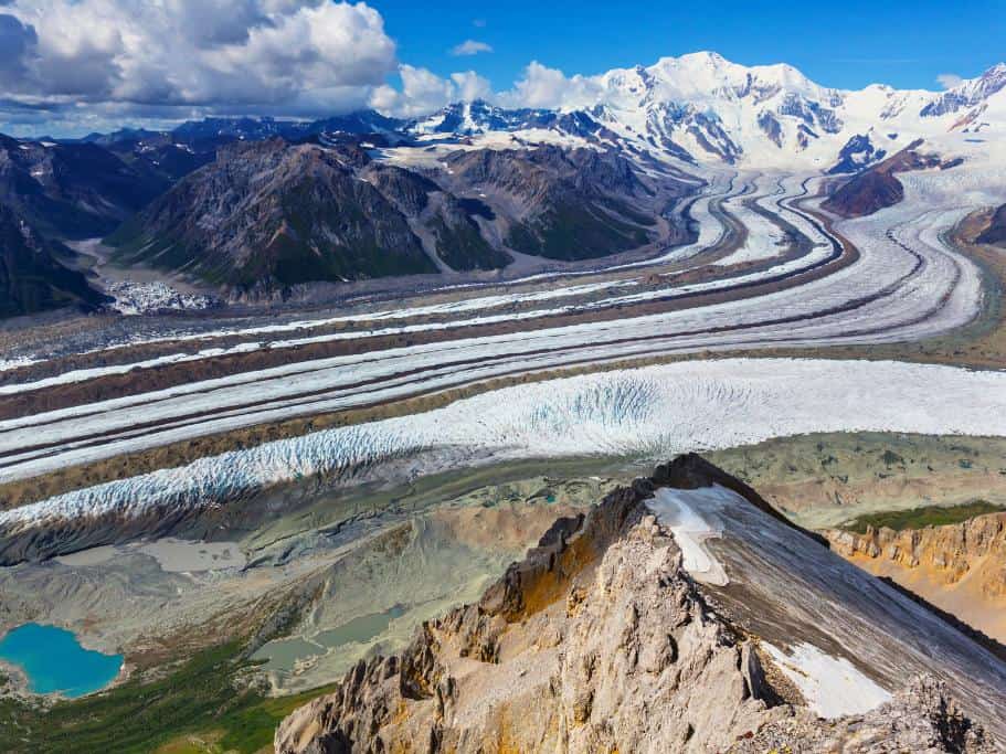 Mountain top overlooking a glacier with snowy mountains and a glacial lake