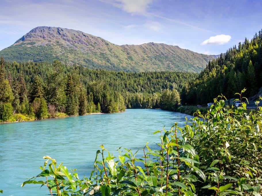 A turquoise blue river surrounded by lush greenery and mountains