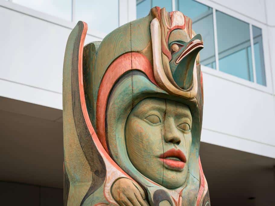 A red and green wooden native structure set against a modern building