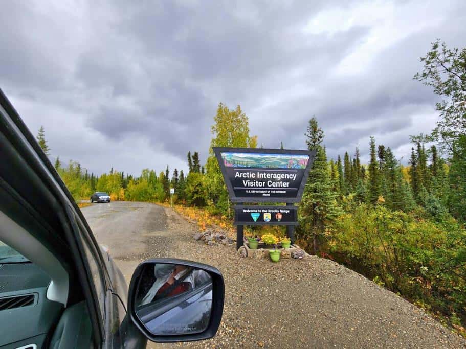 Car window and mirror with a black "Arctic Interagency Visitor Center" sign