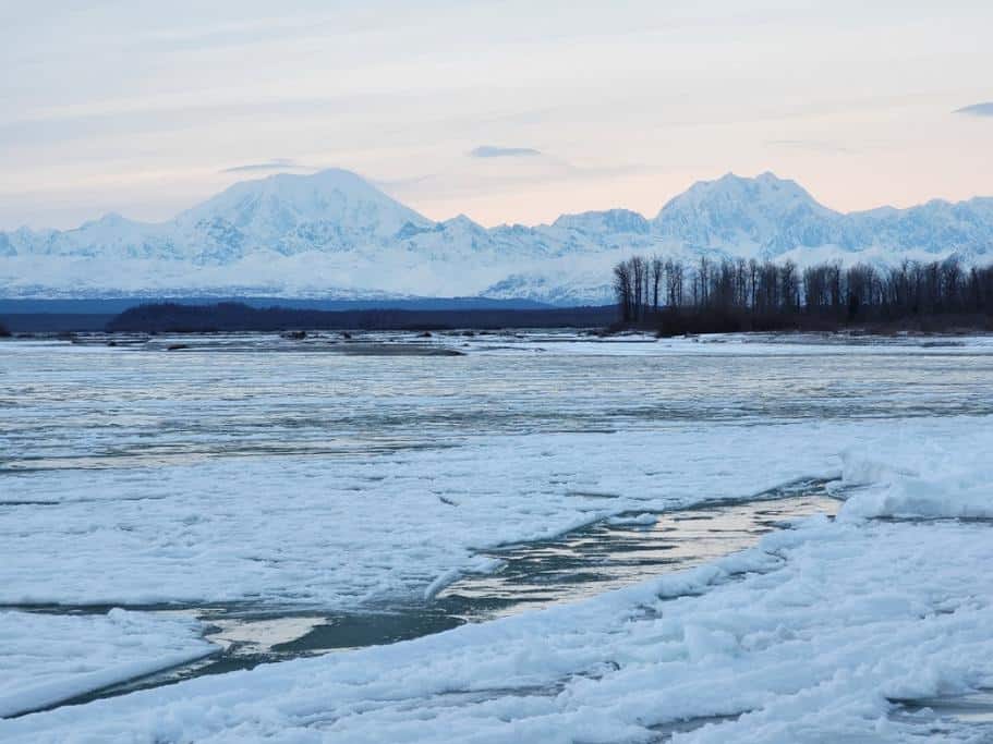 Winter scene with icy water and snowy mountains