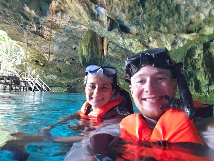 Man and a woman in orange life jackets snorkeling in a cenote