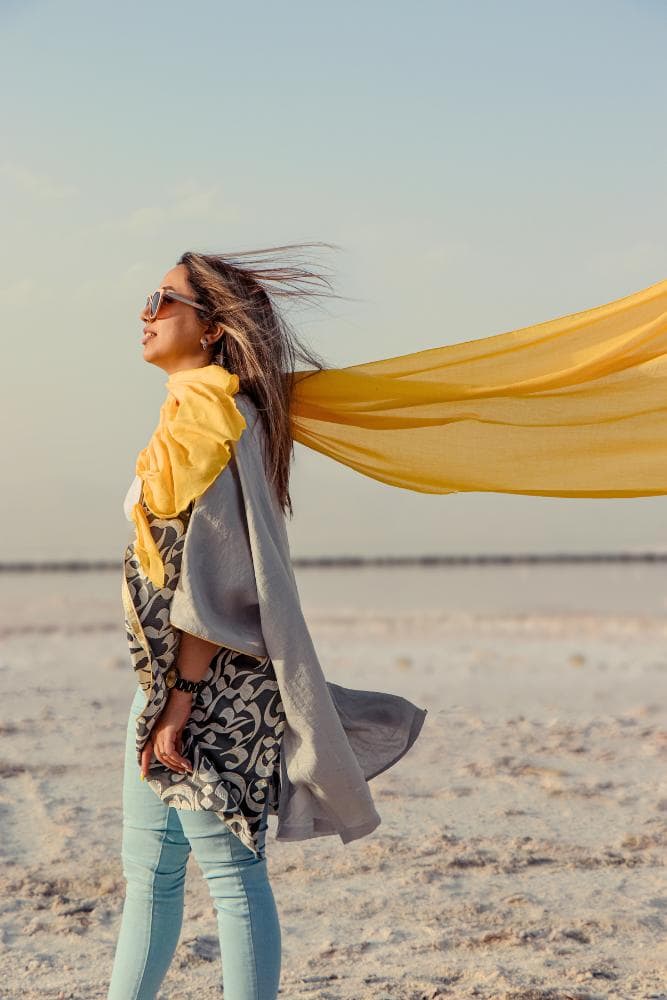 Girl on a beach with a long yellow scarf