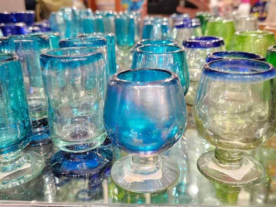 Blue, white, and green glassware on a glass shelf