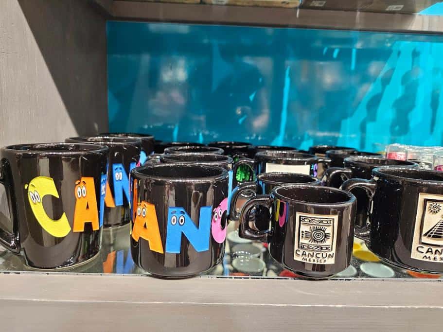 Shelf of black "Cancun" mugs