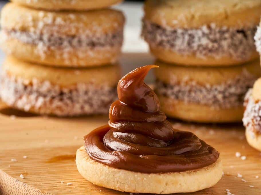 Stacks of coconut-coated cookies with a large dollop of dulce de leche