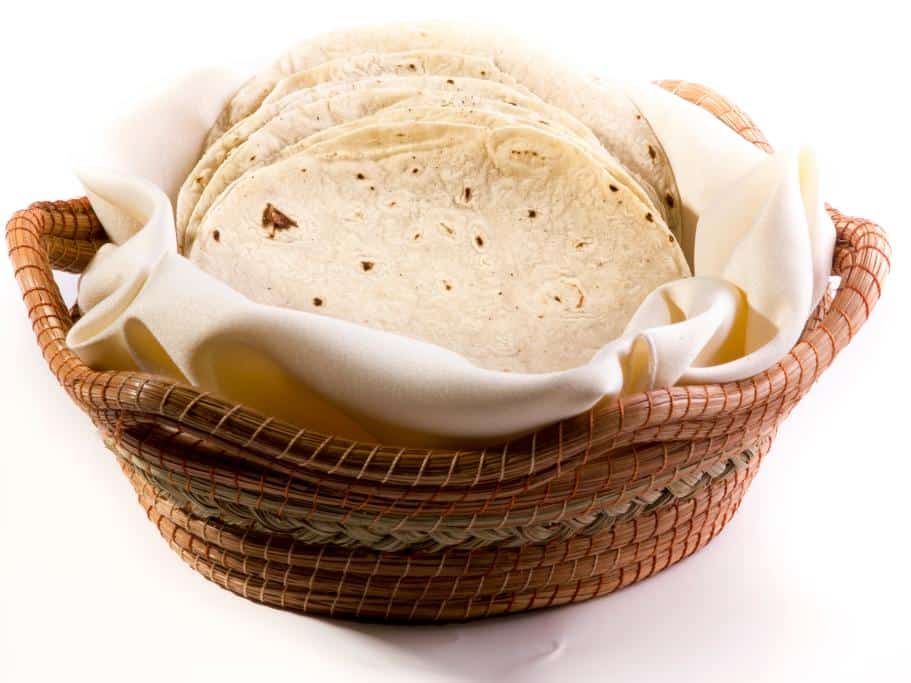 Brown woven basket filled with a white cloth and white torilla shells