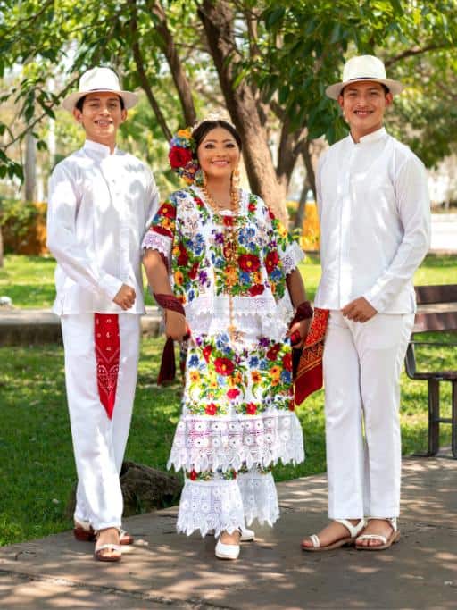 Two men and a woman in traditional white and colorful Mexican clothing