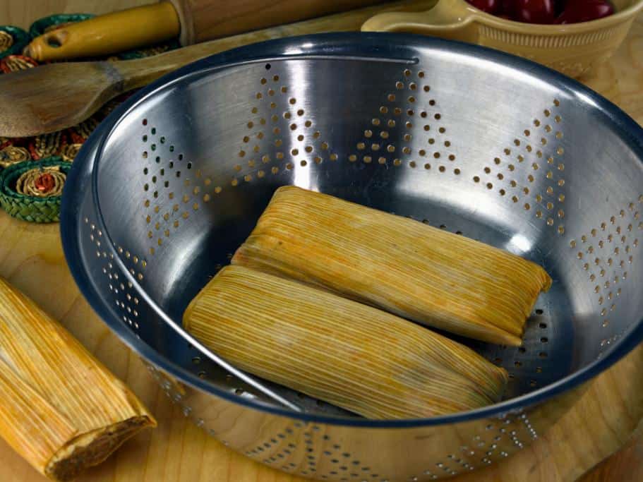 Silver metal steamer with two tamales inside