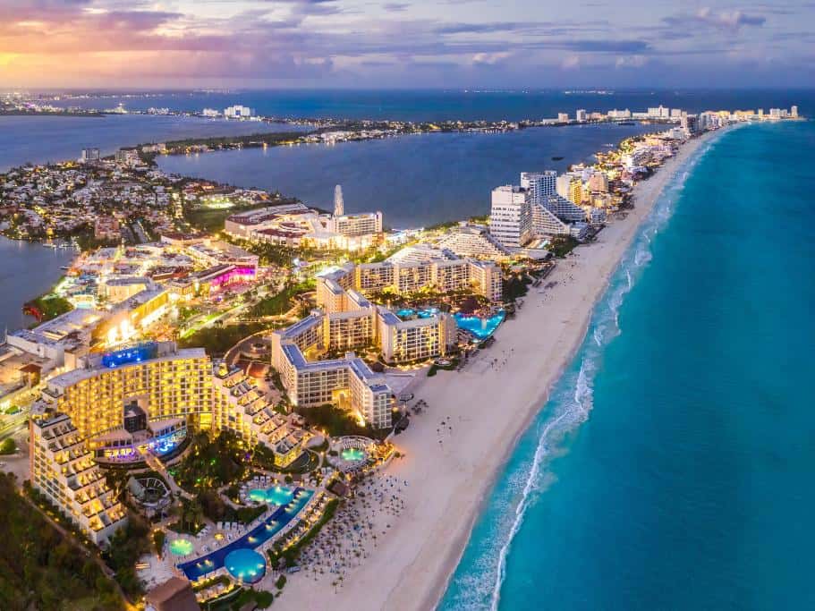 Nighttime aerial view of a long beach with lit up resorts