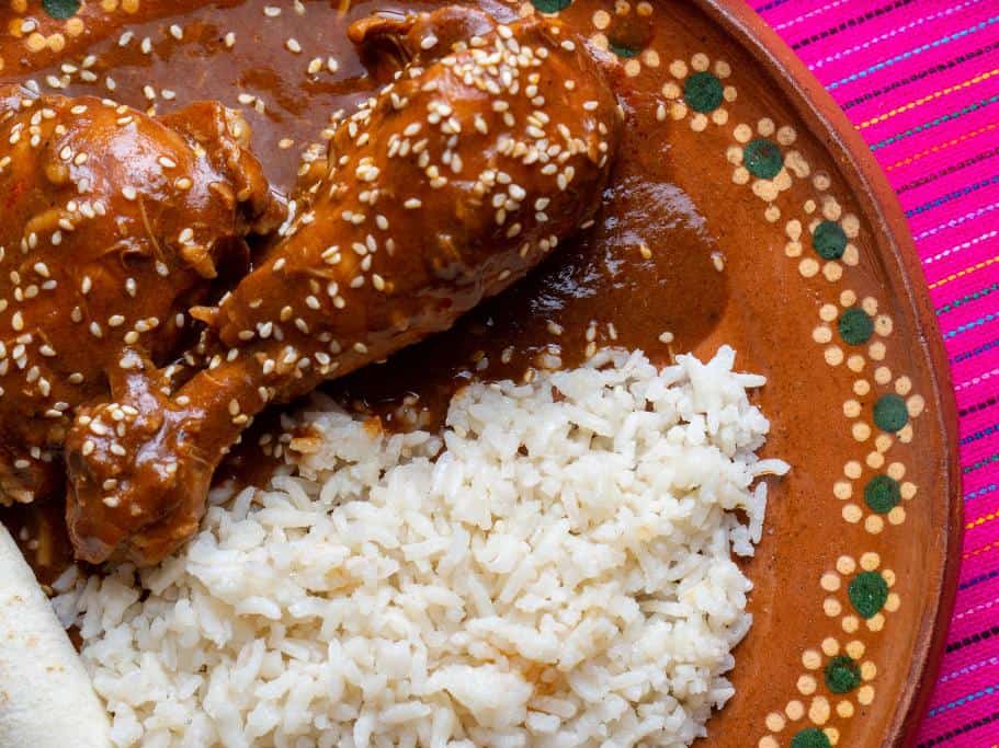 Pink tablecloth, brown plate with painted flowers and rice and chicken covered in brown sauce