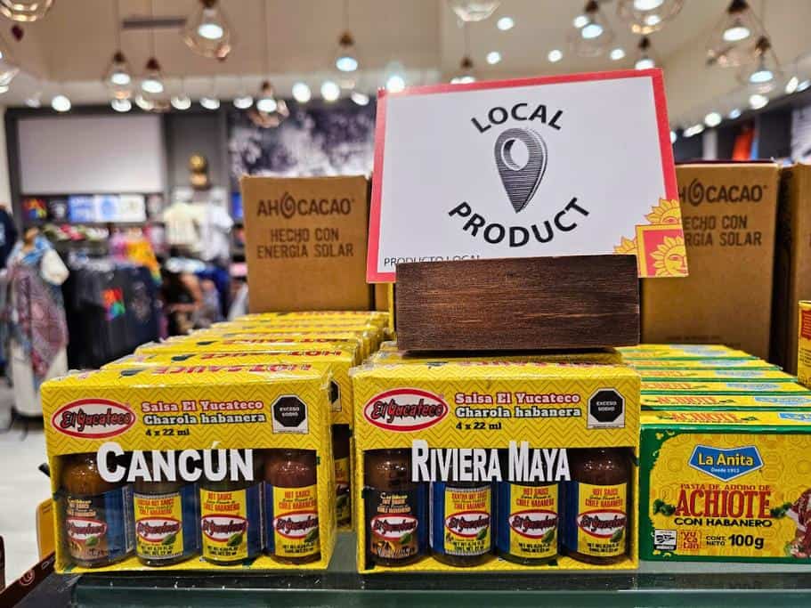 Red and white sign saying "local product" above a variety of hot sauces in yellow boxes