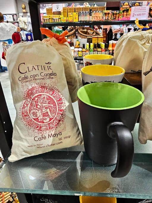 Bag of coffee beans next to a black and green mug on a glass shelf