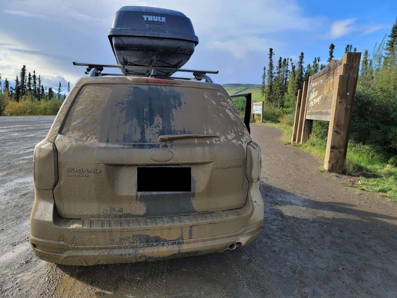 A very muddy back of an SUV on a dirt road