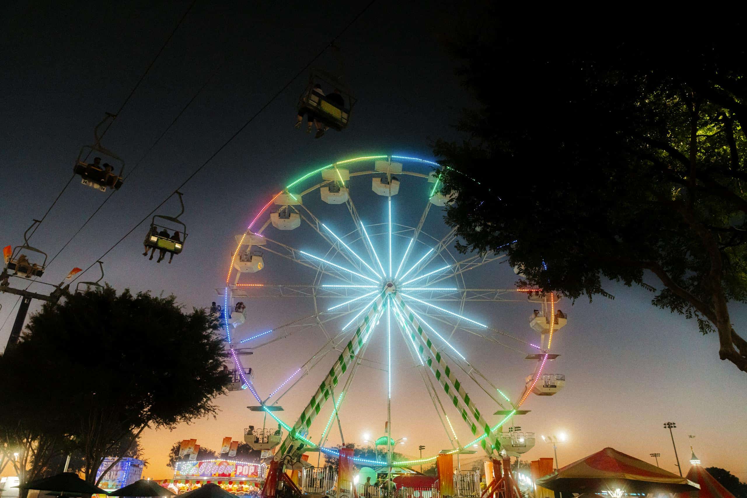 Colorful Ferris wheel glowing at twilight in Costa Mesa fairgrounds, creating a captivating night scene.