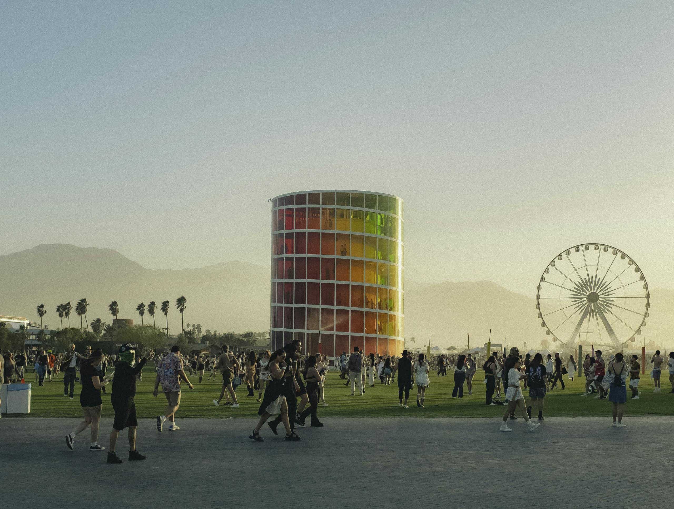 People enjoying a lively music festival with a colorful tower and Ferris wheel backdrop.