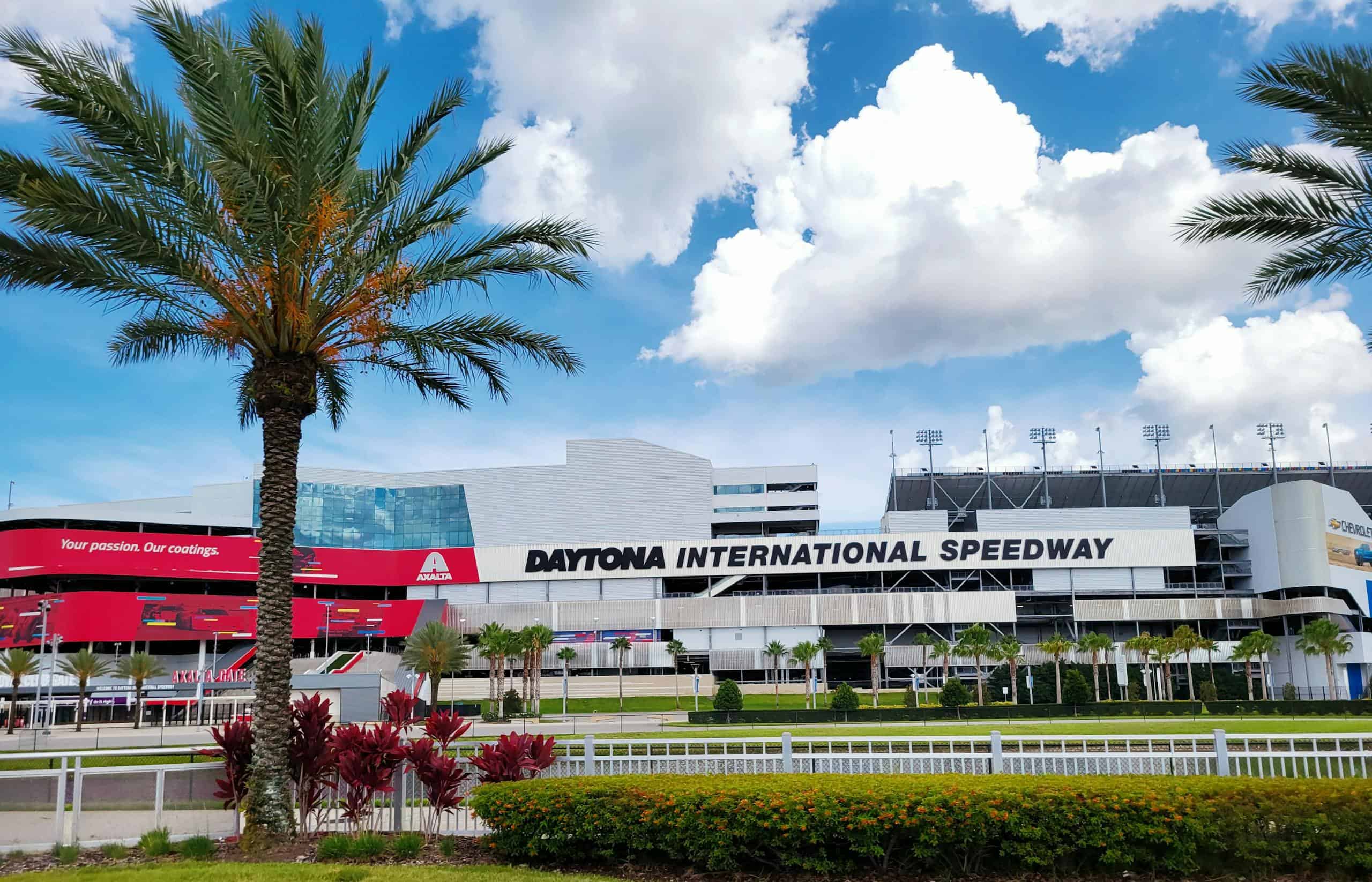 Stunning view of Daytona International Speedway with palm trees and clear blue skies emphasizing the iconic race track.