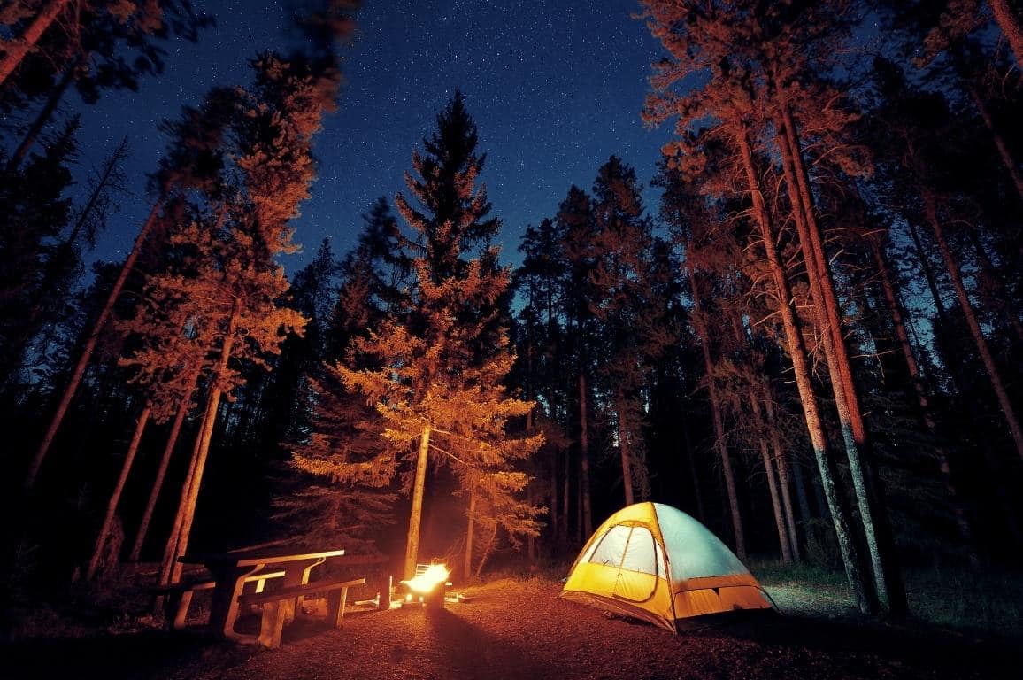 Evening shot of a yellow tent and a burning fire at a campsite in Banff National Park