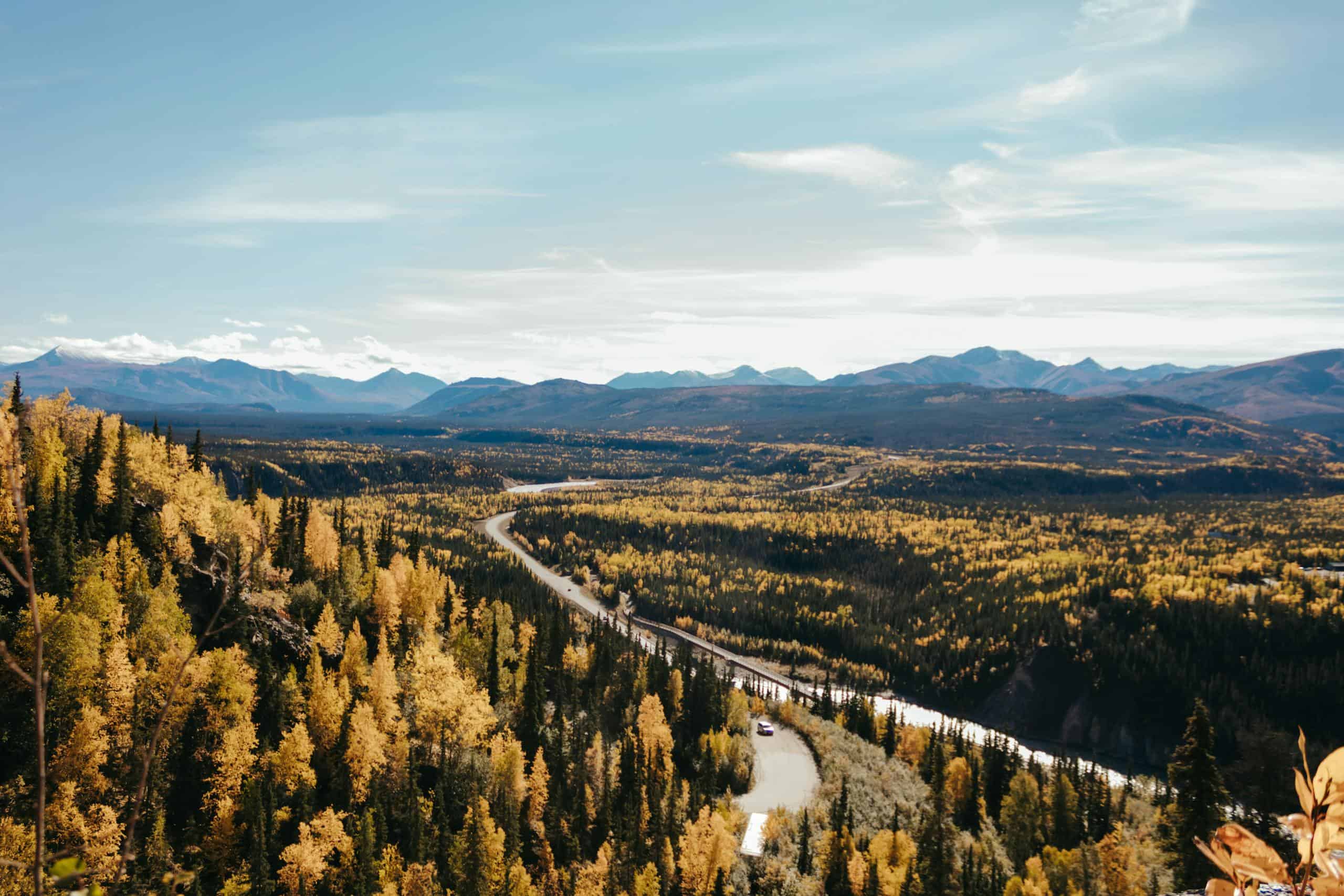 Stunning aerial view of autumn foliage and winding river in Alaska's picturesque wilderness.
